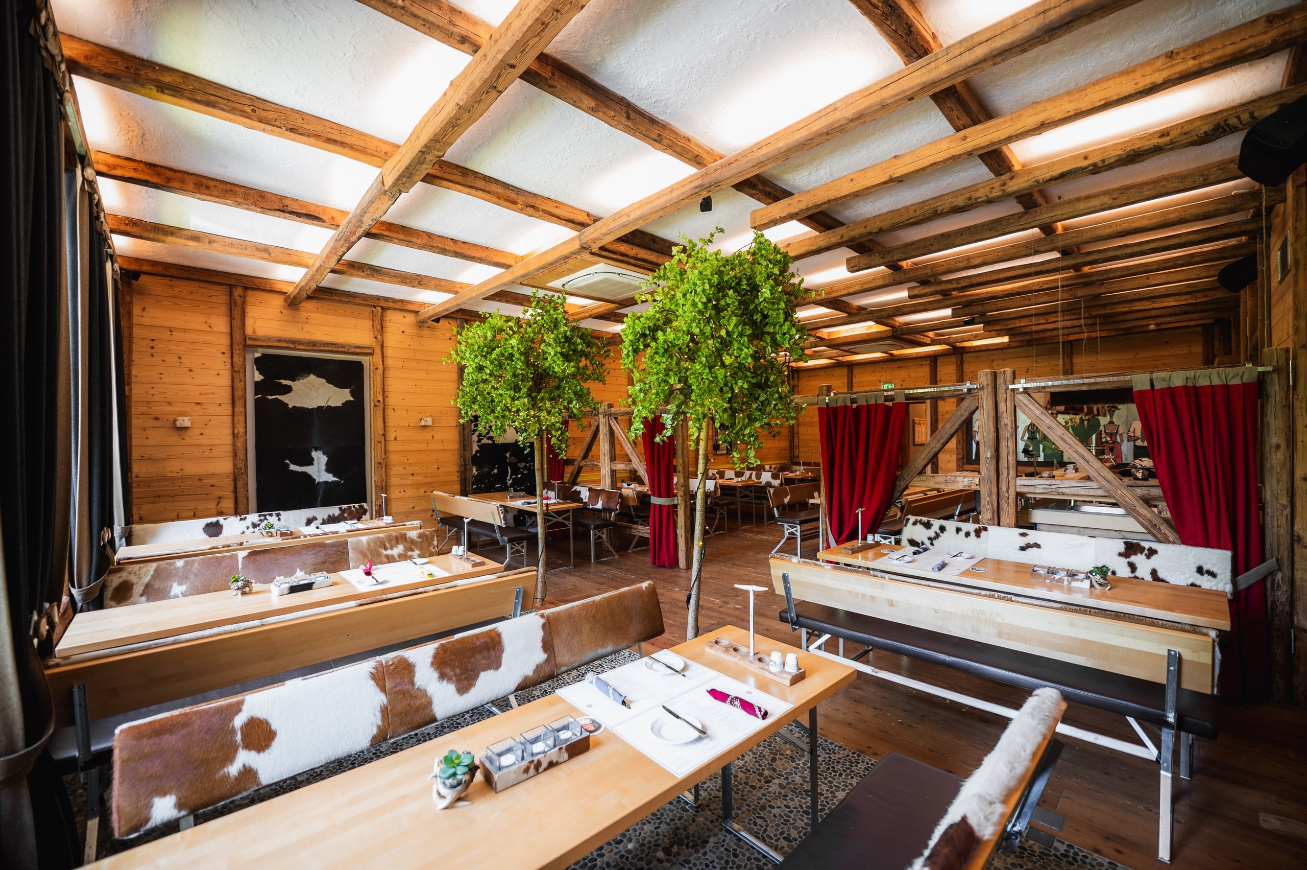 Indoor-Biergarten mit langen Holztischen unter offenem Dachstuhl